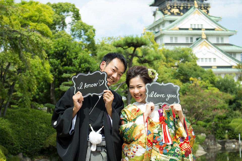 大阪城をバックに「I love you」「I know」のプレートを持ったお二人